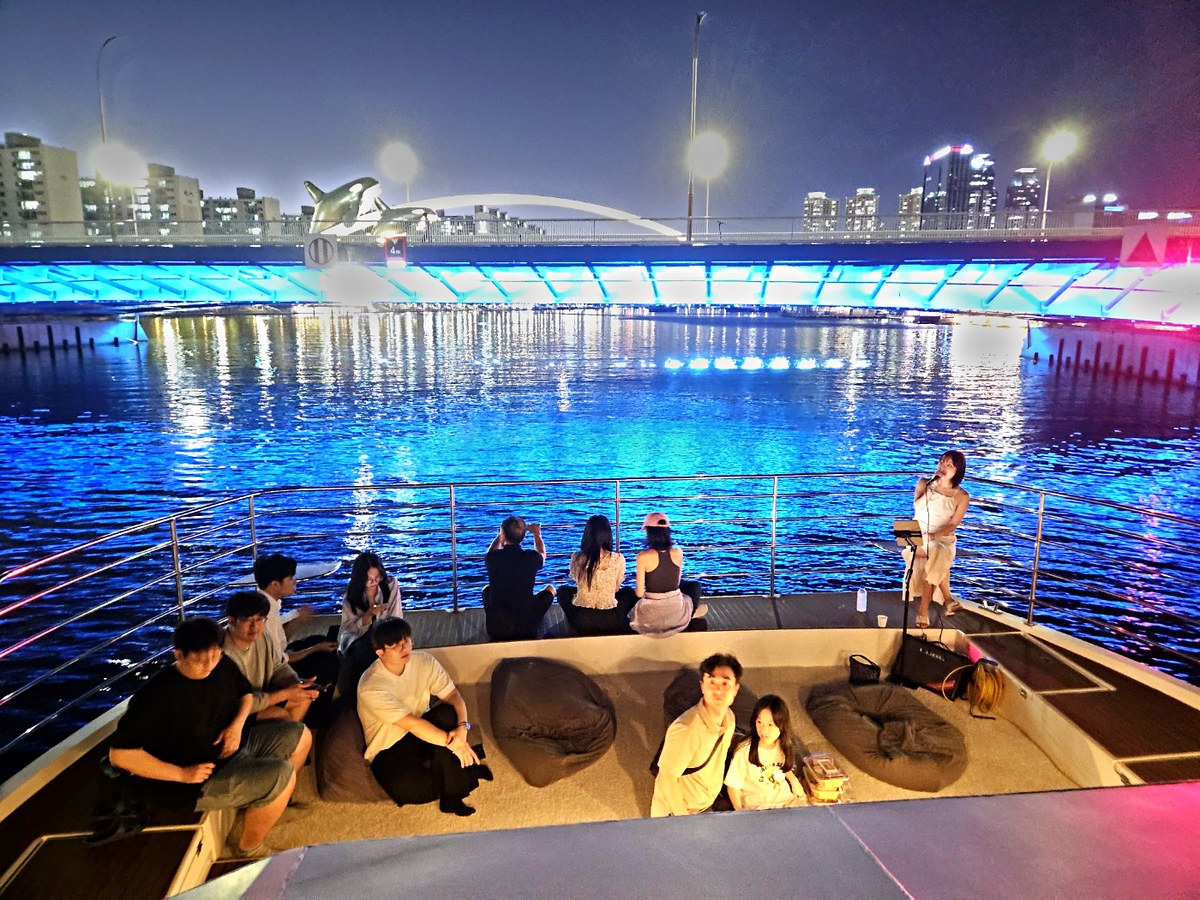 ドローンショーが広がる夜の海、船首デッキの団体のお客様