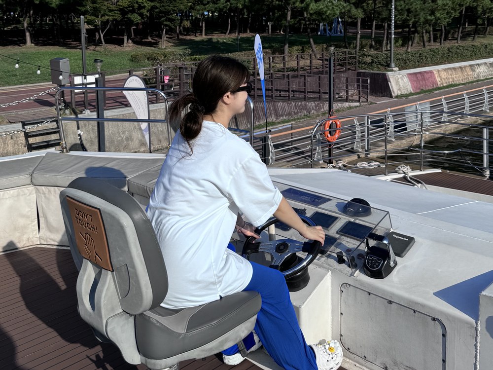 操舵室で船長と一緒に舵を握る子どもの乗客